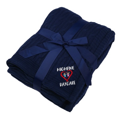 Navy blue cable knit blanket with embroidered design.