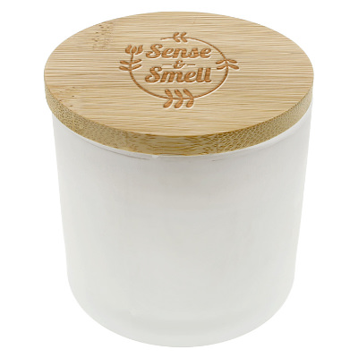 White glass candle with a branded logo.
